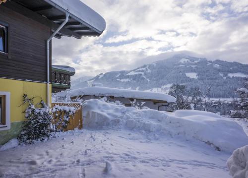 a house covered in snow with a mountain in the background at Latina II in Westendorf
