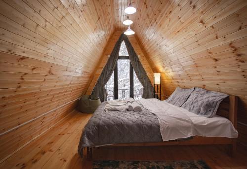 a bed in a wooden room with a window at M&L in Mestia