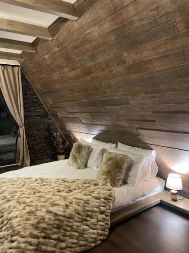 a bedroom with a large bed with a wooden wall at Valea Mosului - Cozy A Frame in Petroşani