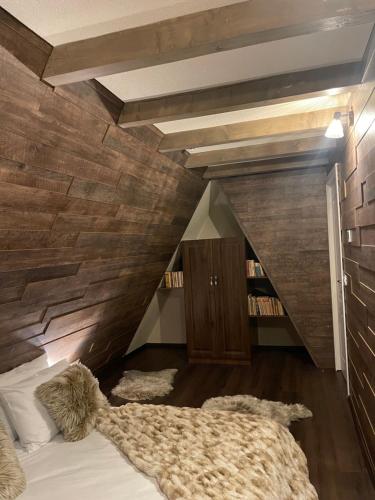a bed in a room with a wooden wall at Valea Mosului - Cozy A Frame in Petroşani