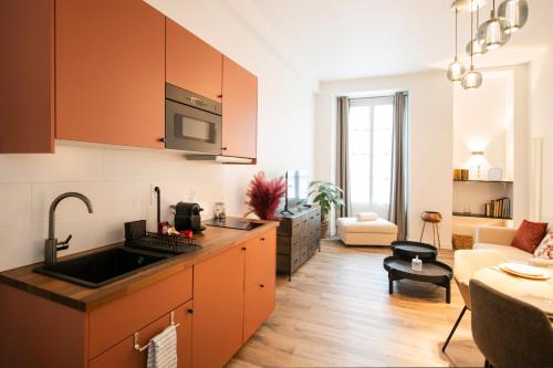 a kitchen with orange cabinets and a living room at Le Laurencin Sens - Le Peachy - Cœur de ville in Sens