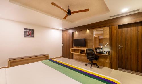 a bedroom with a bed and a desk and a television at Treebo Golden Swan Pammal in Chennai