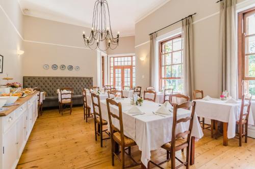 a dining room with tables and chairs and a chandelier at Bonne Esperance Boutique Guest House in Stellenbosch
