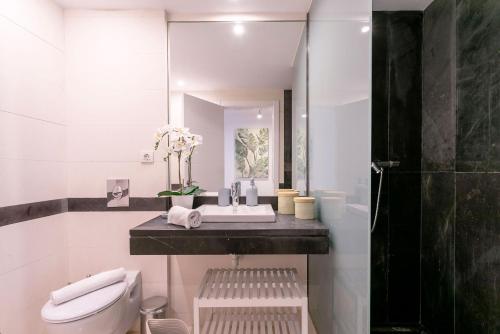 een badkamer met een wastafel, een toilet en een spiegel bij Genteel Home San Agustín in Málaga