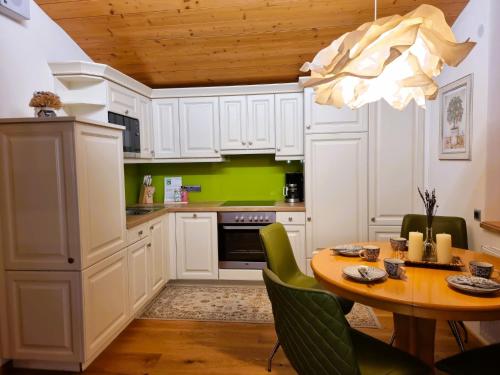 une cuisine avec des placards blancs et une table avec des chaises dans l'établissement Apartment Rätia II by Interhome, à Pfunds