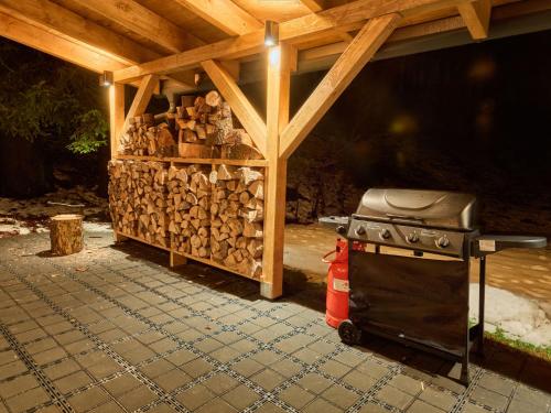 a stove with a pile of fire wood under a roof at Chalet Luxe Timber Lodge & Relaxing Bath by Interhome in Mladé Buky
