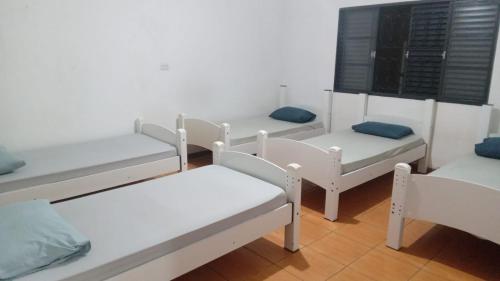 un grupo de camas y sillas blancas en una habitación en Pousada Alvinópolis en Atibaia