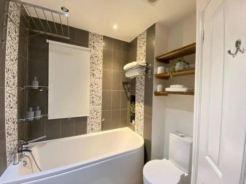a bathroom with a white tub and a toilet at Spacious 2 bed flat ideal for long stays in Purfleet