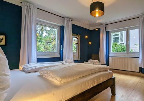 um quarto com 2 camas com paredes e janelas azuis em 65qm Altbaucharme mit zwei Balkonen em Karlsruhe