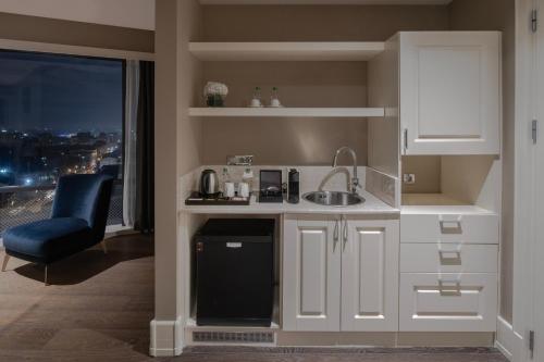 a kitchen with white cabinets and a sink and a window at Windsor Hotel & Convention Center Istanbul in Istanbul