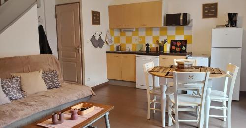 a living room with a couch and a table and a kitchen at Le Canal Wi-Fi Parking Jardin Piscine 15 mn de Béziers in Colombiers