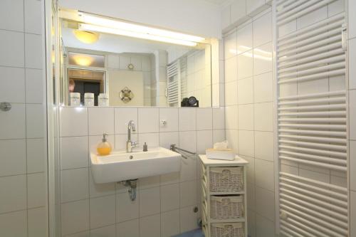 a white bathroom with a sink and a mirror at Haus Metropol 175 OB in Westerland (Sylt)