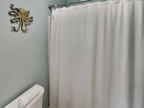 - un rideau de douche blanc dans la salle de bains pourvue de toilettes dans l'établissement Cozy Coconut, à Port Aransas