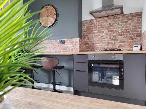 a kitchen with a stove and a clock on the wall at Stay @ The Old Bank Apartments, Burton on Trent in Burton upon Trent