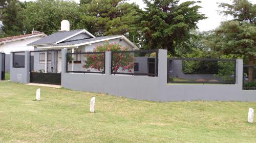 una casa blanca con una valla y un patio en La esquina de Gesell en Villa Gesell