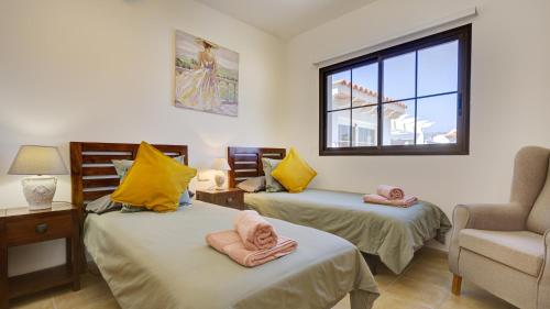 La Guirra的住宿－CASA LOTTIE，客房设有两张床、一把椅子和窗户。