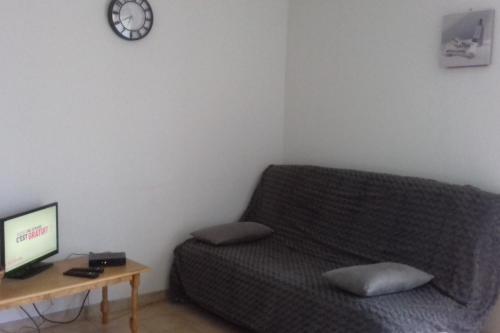 sala de estar con sofá y mesa con reloj en Le Tilleul en périogord Noir proche Sarlat, en Paulin