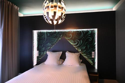 een slaapkamer met een bed en een kroonluchter bij LOGIS Hôtel Borel in Duinkerke