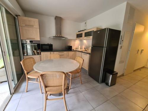 une cuisine avec une table, des chaises et un réfrigérateur dans l'établissement Superbe T2, à 5 min de la plage, avec garage, à La Grande Motte