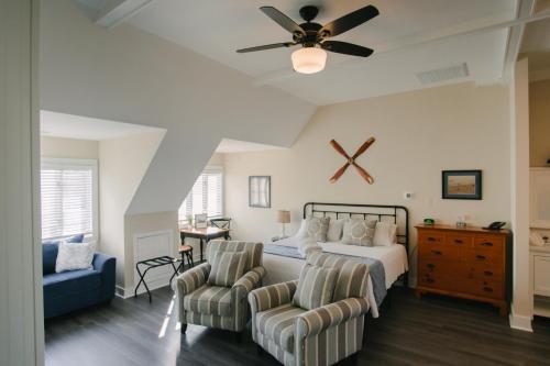 a bedroom with a bed with two chairs and a ceiling fan at Wild Horse Inn in Corolla