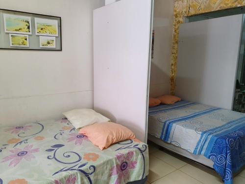 a small bedroom with two beds and a mirror at Kitnet no 1º Piso, a 300m da Praia do Morro in Guarapari