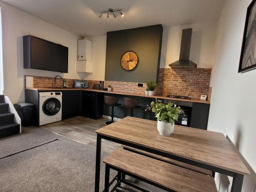 a kitchen with a table and a clock on the wall at Stay @ The Old Bank Apartments, Burton on Trent in Burton upon Trent
