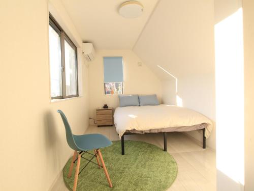 a bedroom with a bed and a blue chair at New building Shinjuku area town house in Tokyo