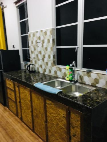 - un comptoir de cuisine avec évier et 2 fenêtres dans l'établissement The Pines House @ PCB (home stay), à Kota Bharu