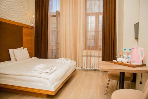 a bedroom with a bed and a desk and a table with a chair at Solo Hotel in Baku
