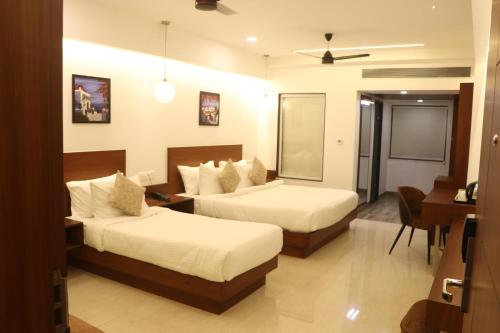 a hotel room with two beds and a desk at HOTEL KADAMB TREE in Jabalpur