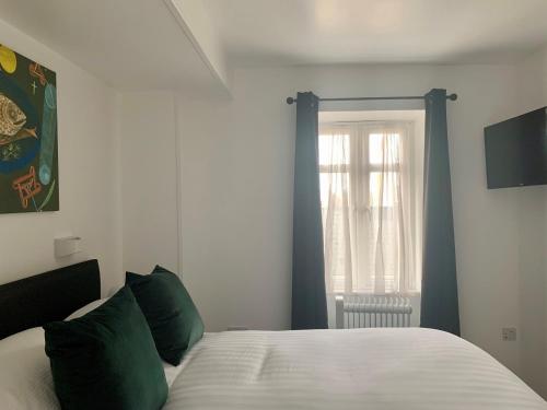 a white bed with green pillows in a bedroom at Sarum Apart-Hotel in Saint Helier Jersey