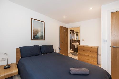 a bedroom with a blue bed and a bathroom at Urban Oasis with Views in Old St in London