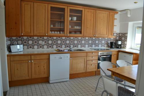 a kitchen with wooden cabinets and a white dishwasher at Immensee App B in Ehst