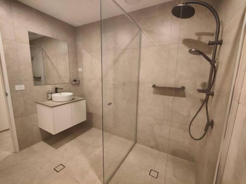a bathroom with a glass shower with a sink at Brand New 2B1B Apt @ Inner North of Canberra in Canberra