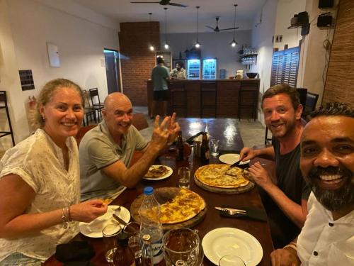 a group of people sitting around a table eating pizza at Kenno's Korner in Weligama