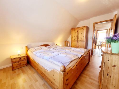 Un dormitorio con una gran cama de madera con sábanas blancas. en Am Seedeich, en Vollerwiek