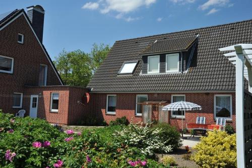 a brick house with a garden and an umbrella at Am Seedeich in Vollerwiek
