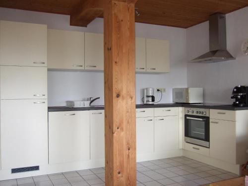 a kitchen with white cabinets and a wooden pole at Nickelswarft 1 in Poppenbüll