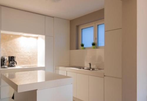 een witte badkamer met een wastafel en een spiegel bij Appartement Nieuwpoort-Bad met garage in Nieuwpoort