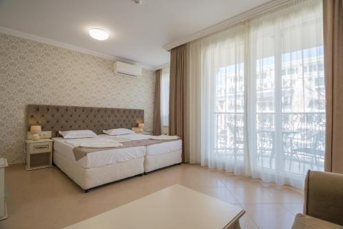 a bedroom with a bed and a large window at Rena Hotel - All Inclusive in Sunny Beach