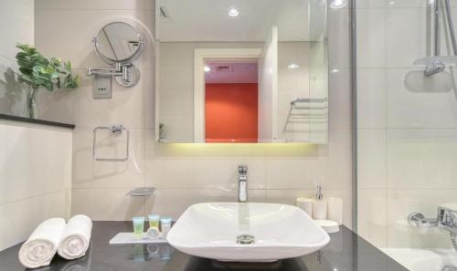 a white bathroom with a sink and a mirror at Luxury Hotel Apartment - DownTown in Dubai