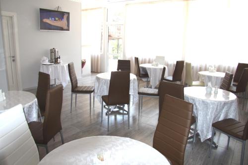 un comedor con mesas y sillas blancas en Vinograd Hotel, en Sochi