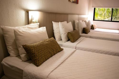 two beds in a hotel room with white pillows at Iguassu Express Hotel in Foz do Iguaçu