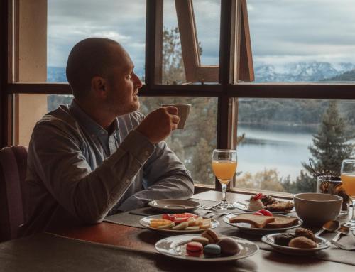 un uomo seduto a un tavolo che beve un bicchiere di succo d'arancia di Boutique Hotel & Spa Bosque del Nahuel a San Carlos de Bariloche