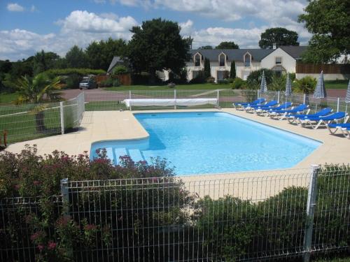 uma piscina com cadeiras e uma cerca em Gîte 5 avec piscine - plage 3kms em Clohars-Carnoët