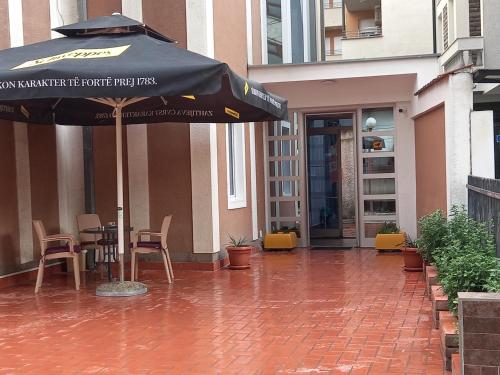 a patio with an umbrella and a table and chairs at Hotel Peja in Peje