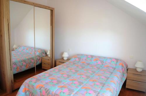 een slaapkamer met een bed en een spiegel bij Gîte 1 avec piscine - plage 3kms in Clohars-Carnoët