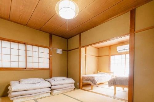 a room with two beds and a ceiling with a light at HAT京終、京終駅徒歩４分。奈良公園・奈良町へ行くのにおすすめ！ in Mitsugarasuchō