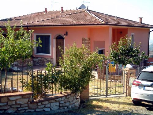 a house with a fence and a car parked in front at Casa Papacqua in Castellina Marittima