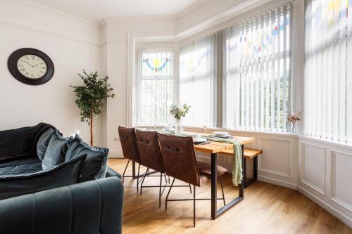 - un salon avec une table, des chaises et une horloge dans l'établissement Beech Suite with 85 inch Cinema TV, à Bradford